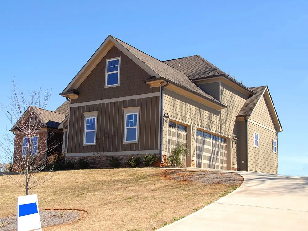 A two-storey suburban house with a sign in the front yard