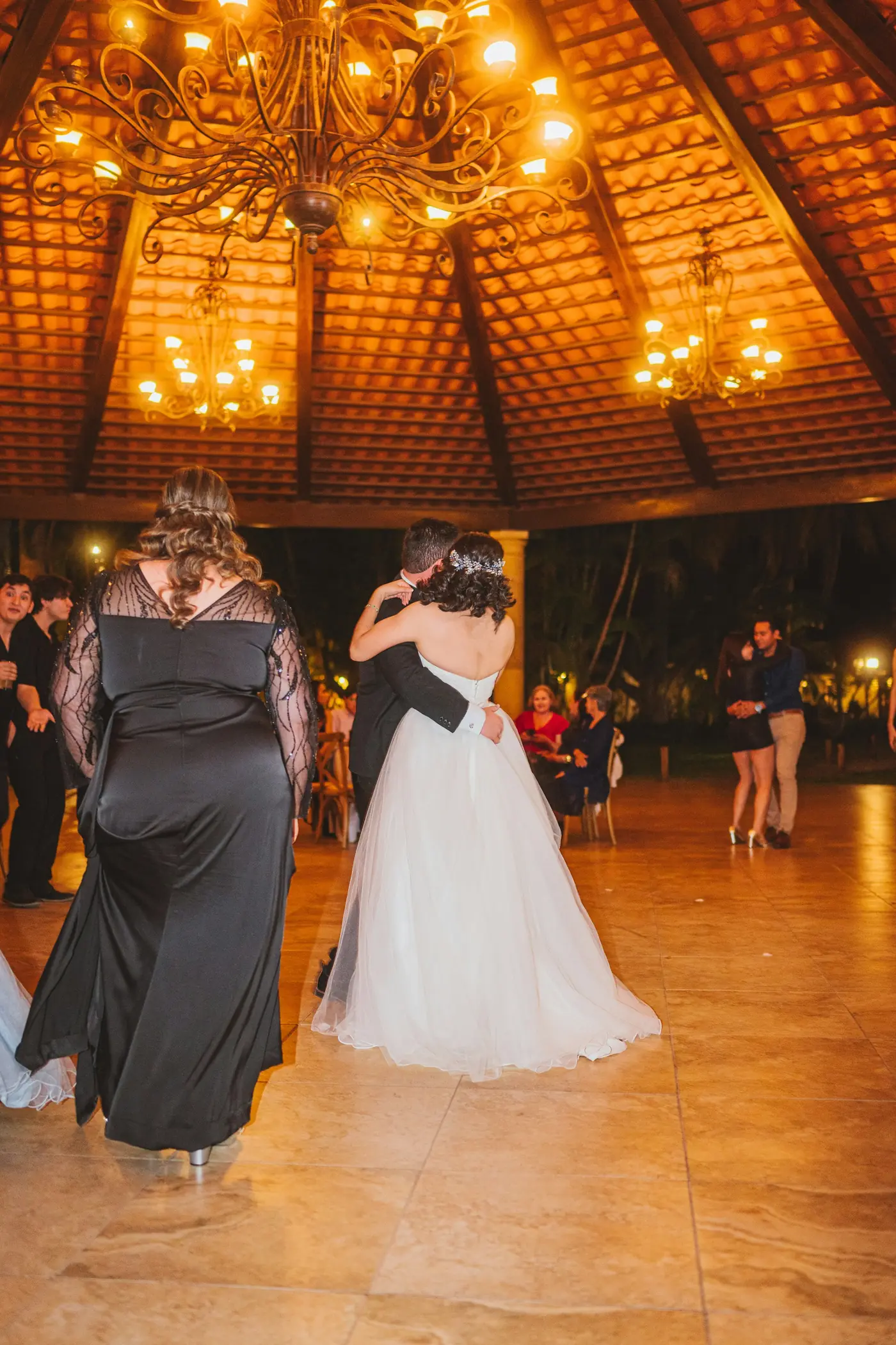 A couple dancing under a chandelier at their reception
