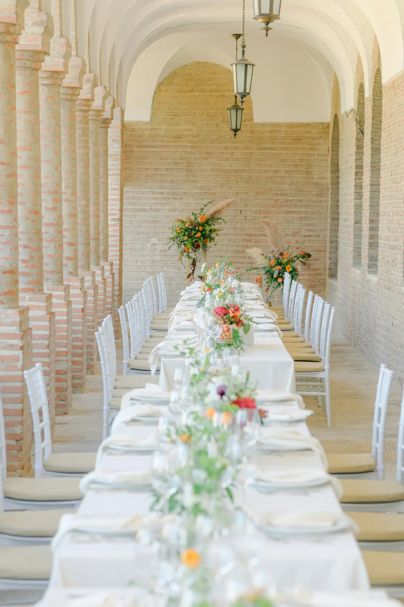 A long table set with flowers in an arched white hall